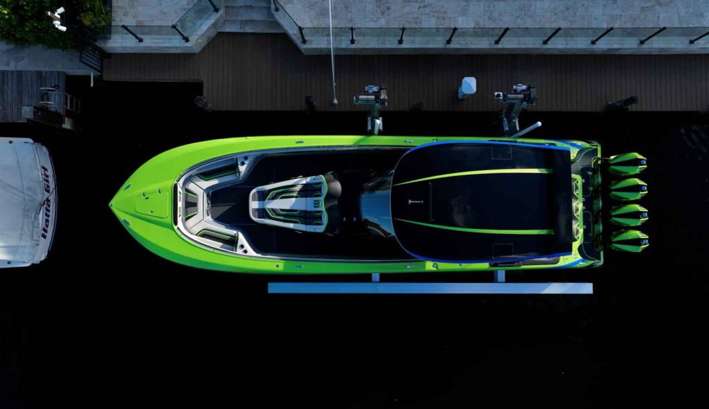 Overhead view of a green and blue performance boat with four outboards on an elevator boat lift.