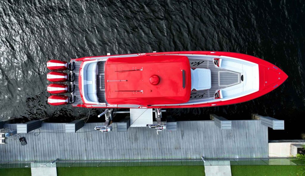 Overhead view of a red performance boat with four outboard engines on an elevator boat lift.
