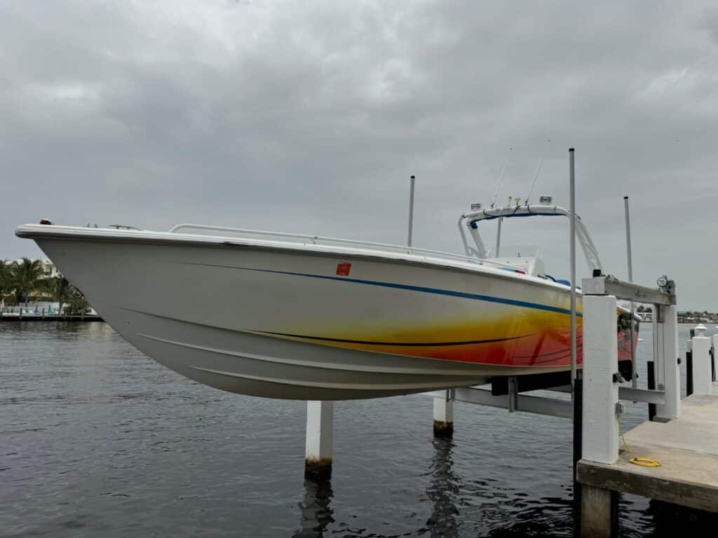 Performance boat with red and orange graphics raised on a 4-post boat lift in Pompano Beach.