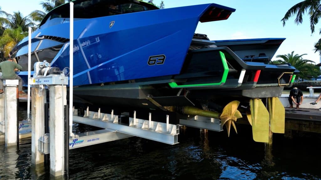 Close-up of the stern and propellers of a blue Lamborghini yacht on an 8-post boat lift in Fort Lauderdale.