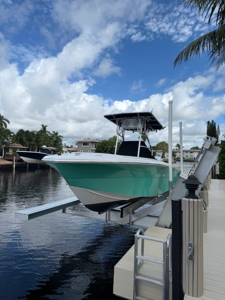 Seafoam green center console raised on an elevator boat lift in Pompano Beach.