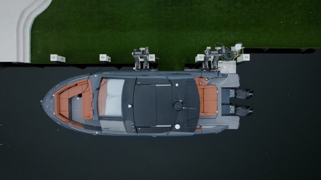 Top-down view of a gray runabout with orange upholstery on an elevator boat lift.