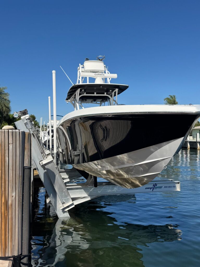 Boat with a black and white hull and fishing tower raised on an elevator boat lift in Pompano Beach.