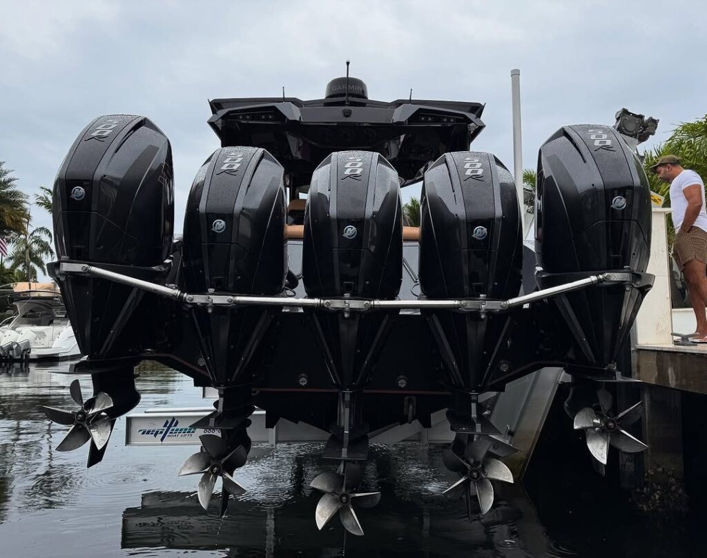 Rear view of a boat with five black outboard engines raised on an elevator boat lift.